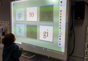 Dziewczynka układa wyrazy z sylab na tablicy interaktywnej